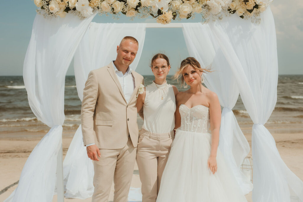 Hochzeitsplanerin mit Brautpaar nach der Trauzeremonie am Strand der Insel Usedom mit Ostsee im Hintergrund