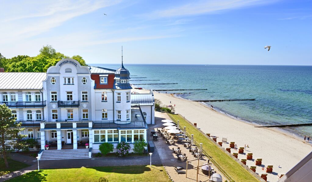 Elegantes Strandhotel mit weißer Fassade, ideal als Hochzeitslocation, eingebettet an Sandstrand und ruhiger blauer Ostsee unter klarem Himmel in Mecklenburg-Vorpommern.